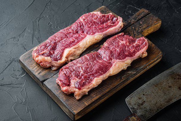 gesneden rauw stuk marmeren rundvlees biefstuk, op zwarte achtergrond - Foto, afbeelding