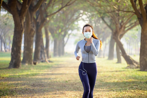  Młoda kobieta w masce i biegająca po parku  - Zdjęcie, obraz