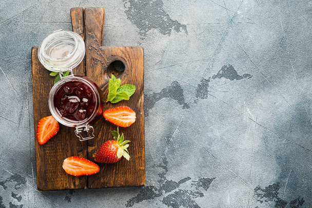 Engarrafamento de morango delicioso caseiro e com berrie fresco, em fundo cinza, vista superior flat lay com espaço de cópia para texto - Foto, Imagem
