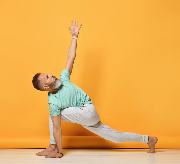 oga man. Man doing yoga on a yellow background - Foto, afbeelding