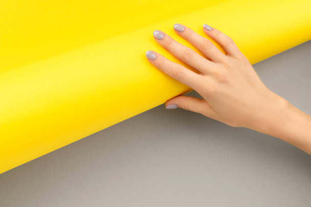 Beautiful womans hand with shiny nail design on gray and yellow background - Foto, Bild