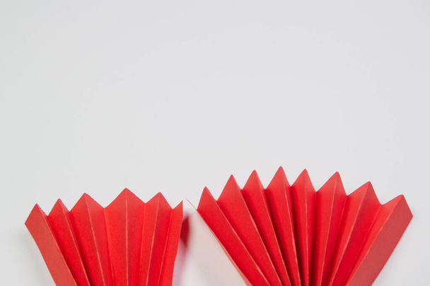 Red origami paper fans, located at the bottom edge on a white background, copy of the space. - Foto, Bild
