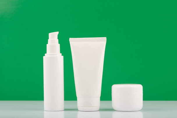 Organic cosmetic products set for daily beauty routine on white glossy table against green background - Фото, зображення