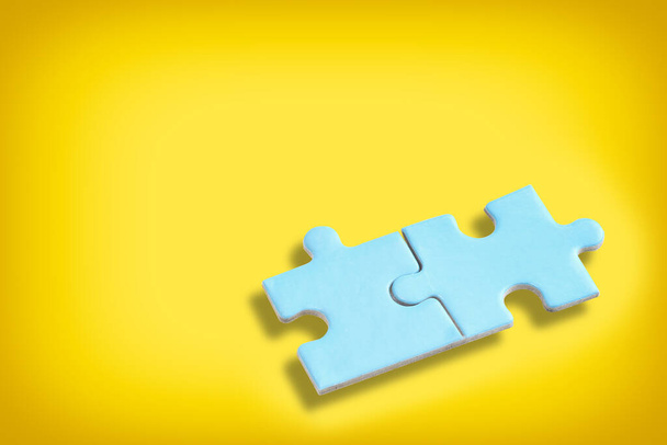Niebieski puzzle układanki z cieniem na żółtym tle. Koncepcja partnerstwa biznesowego i wspólne rozwiązywanie problemów - Zdjęcie, obraz