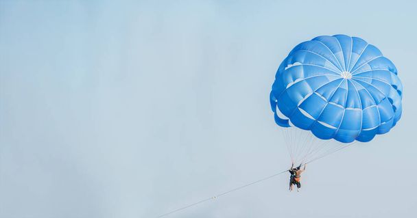 Человек, летящий в небе на парашюте. Активная концепция спорта. Концепция путешествия и отдыха. - Фото, изображение