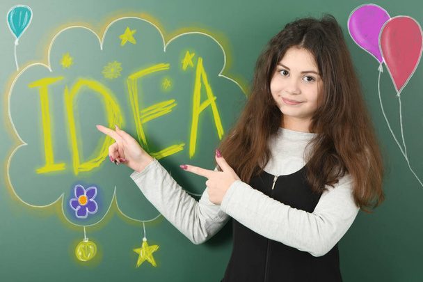 Niño pre-adolescente señala la palabra "idea" que pintó en la junta escolar - Foto, imagen