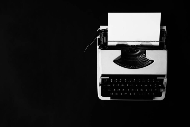 друкарська машинка з чистим аркушем паперу на чорному тлі
 - Фото, зображення