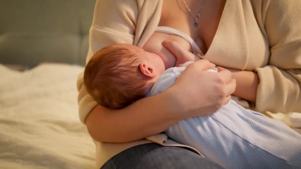 Schattige kleine pasgeboren baby zuigende melk van moeders borst zitten op 's nachts. Concept van gezonde en natuurlijke babyvoeding. Gezondheid van moeder en kind. - Video