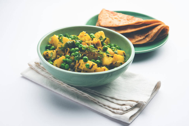 Aloo Mutter veya Matar aalu dry sabzi, Hint Patatesi ve yeşil bezelyeler baharatla kızartılmış ve kişniş yapraklarıyla süslenmiş. Roti veya chapati ile servis edilir. - Fotoğraf, Görsel