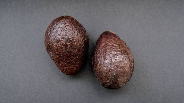 Due avocado hass su sfondo scuro. Note di alimentazione. Cibo vegano. Dieta vegetariana - Foto, immagini