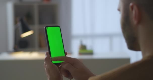 utente maschile è strisciamento visualizzazione di smartphone con schermo verde per la tecnologia chroma key, la visualizzazione di immagini e foto nei social network - Filmati, video