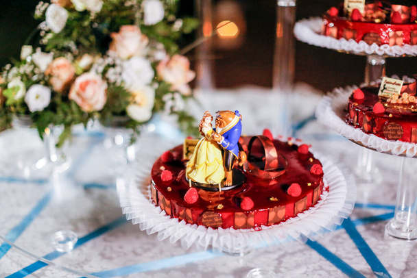 esküvői torta, vörös gyümölcsökkel és figurákkal. Kiváló minőségű fénykép - Fotó, kép