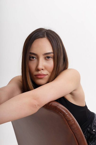portrait of young attractive asian woman with long brown hair sitting on chair - Foto, imagen