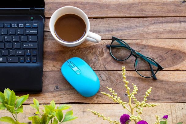 portátil de computadora para el trabajo de negocios con café caliente, ratón, gafas de sol de estilo de vida disposición plana estilo laico sobre fondo de madera - Foto, imagen
