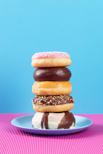 Stack of diferent donuts on pink and blue background.  - Photo, Image