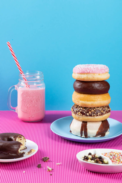 Donuts y batido de fresa sobre fondo rosa y azul. - Foto, imagen