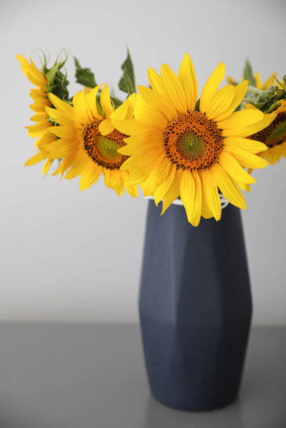 Bouquet of beautiful sunflowers on table near light wall - Фото, зображення