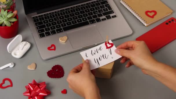 若い男は手書きのカードを置きます私はバレンタインの日のギフトボックスの上にあなたを愛し - 映像、動画