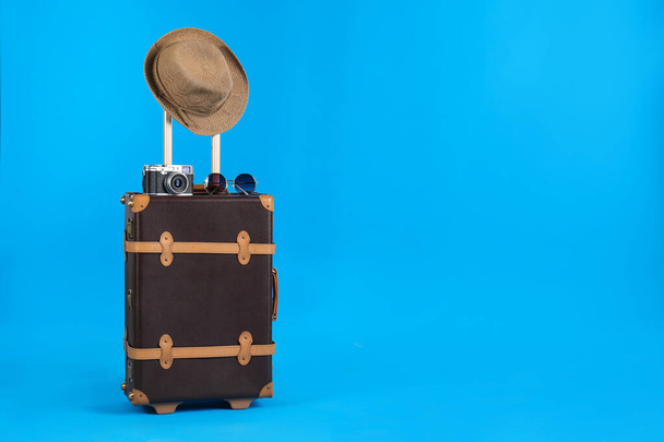 Vintage travel suitcase with hat, camera and sunglasses on light blue background, space for text. Summer vacation - Fotoğraf, Görsel