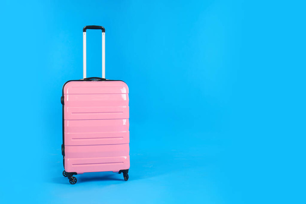 Maleta de viaje rosa sobre fondo azul claro, espacio para texto. Vacaciones de verano - Foto, Imagen
