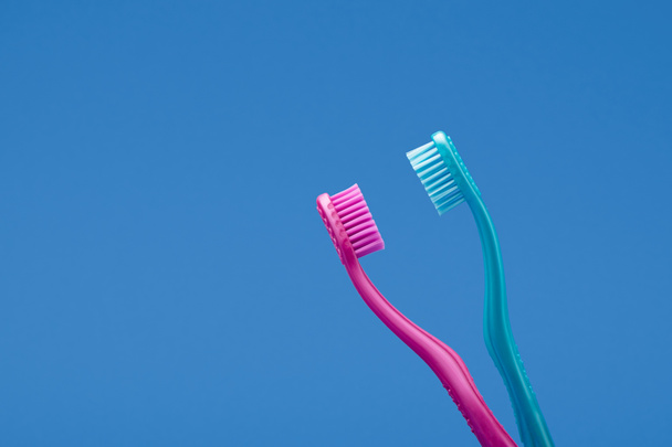 Szenvedély koncepció rózsaszín és kék fogkefék rendezett, mint intim pár kék háttér. - Fotó, kép