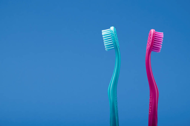 Rózsaszín és kék fogkefe, közöttük távolsággal, úgy rendezve, mint a veszekedő pár. Kék háttér minimális stílus. - Fotó, kép