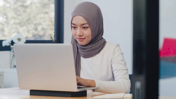 Kaunis Aasia muslimi nainen rento kulumista työskentelee kannettavan nykyaikaisessa uudessa normaalissa toimistossa. Kotona työskentely, etätyö, eristäytyminen, sosiaalinen etäisyys, karanteeni koronaviruksen ehkäisemiseksi. - Valokuva, kuva