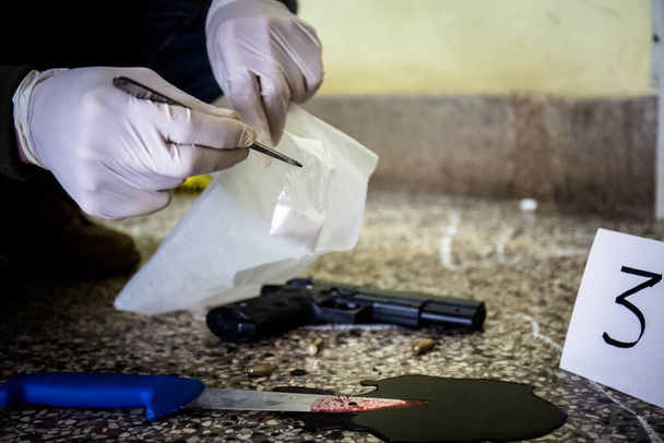 Сцена злочину, вбивство, слідство, поліція знаходять викинуту зброю, яка використовується вбивцею, взята як свідчення вбивства, поліція знаходить наркотики і кривавий ніж
 - Фото, зображення
