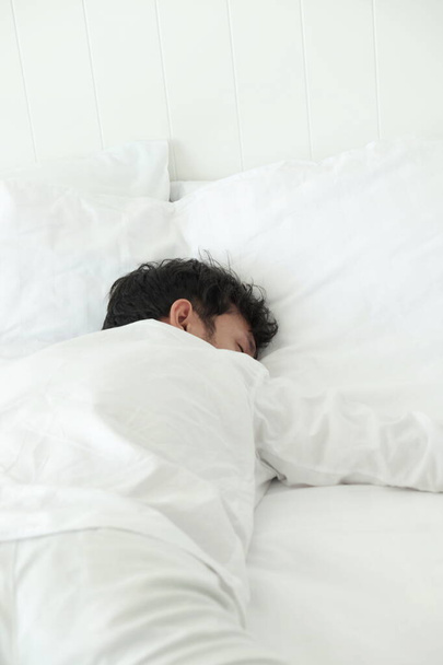Ο άντρας κοιμάται στο κρεβάτι στην κρεβατοκάμαρα  - Φωτογραφία, εικόνα