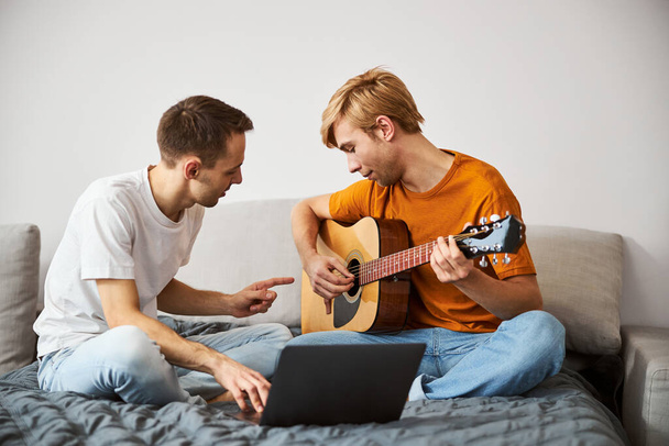 man muzikant spelen gitaar en tijd doorbrengen met vriendje - Foto, afbeelding