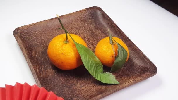 Una mano mette gli appassionati di carta origami rossi su un piatto di legno scuro di mandarini. Sfondo festivo Capodanno cinese, creatività, video 4K. - Filmati, video