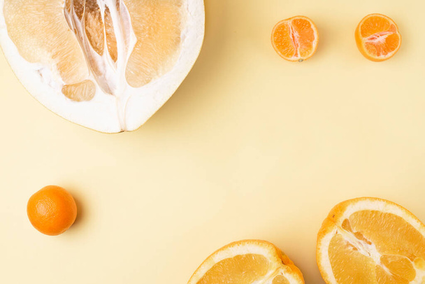Sarı arka planda portakal ve mandalinalı sulu taze zeytinlerin yarısı, yakın plan, kopyalama alanı. Citrus meyveleri. - Fotoğraf, Görsel