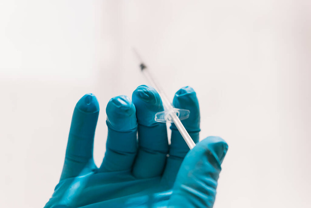 View of the palm of a gloved hand holding a medical syringe. - Photo, Image
