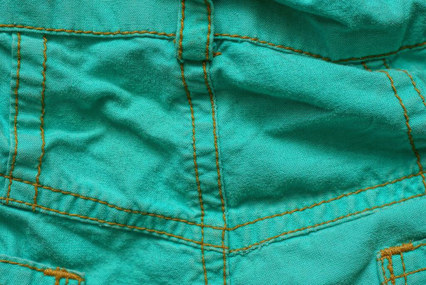 texture verte de tissu froissé sur des vêtements avec une couture de fils jaunes - Photo, image