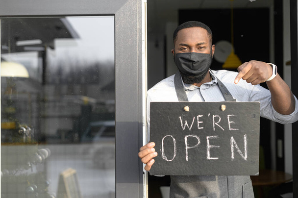 An African waiter in a medical mask with open sign - Foto, Imagem