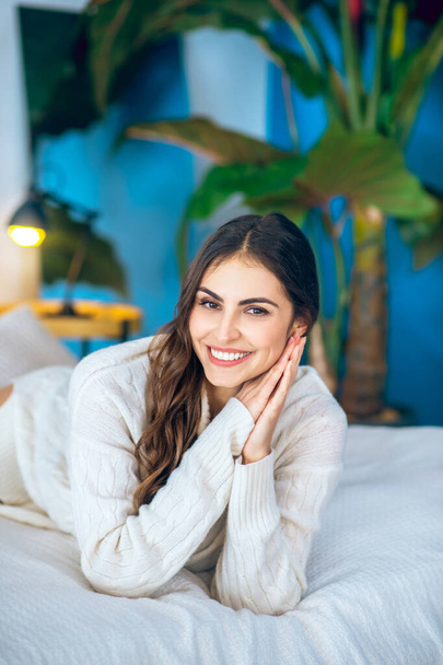 Young beautiful woman lying on bed and smiling nicely - Foto, afbeelding