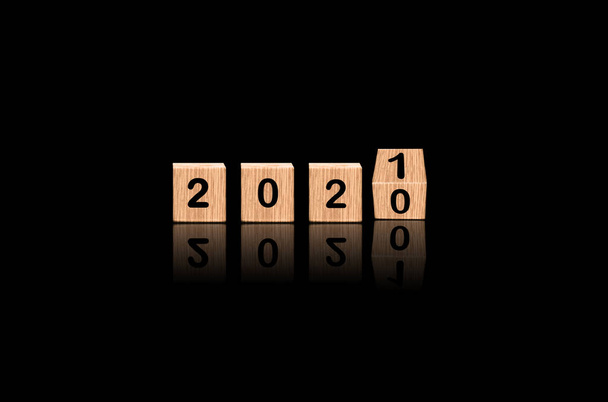 2020 рік - перекинутий до 2021 року, зроблений з блоків дерева на розкішному чорному тлі, Зміна приходить Концепція. - Фото, зображення
