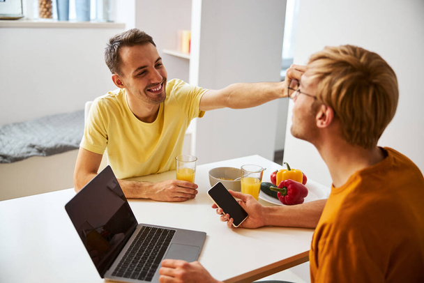 heureux gay couple avoir petit déjeuner et en utilisant moderne gadgets - Photo, image