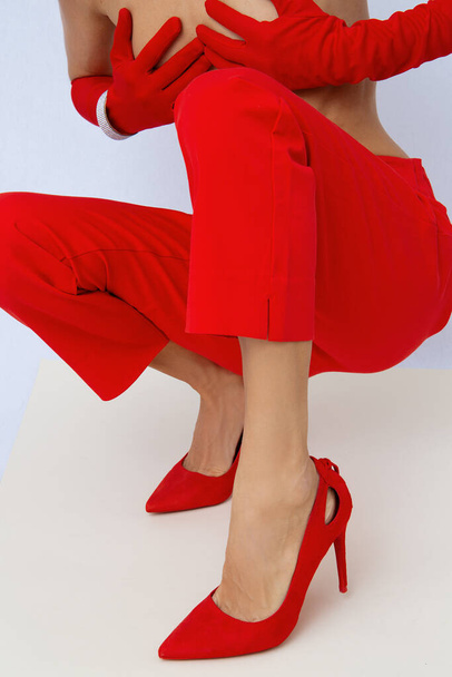 Мода неузнаваемая модель в красных штанах и туфлях. Минималистский элегантный стиль деталей. Ретро перчатки и аксессуары для браслетов. Винтажная эстетика Lookbook. - Фото, изображение