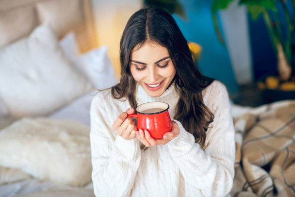 Dark-haired woman with a red cup in her hands looking relaxed - Фото, изображение
