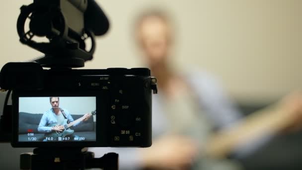 Mężczyzna z półakustyczną gitarą przed kamerą wideo. - Materiał filmowy, wideo