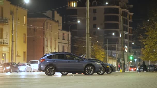Niebieski samochód zaparkowany na jasno oświetlonej ulicy miejskiej z ruchomymi światłami w tle w nocy. - Materiał filmowy, wideo