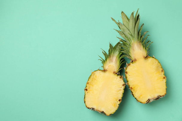 Halves of tasty ripe pineapple on mint background - Fotó, kép