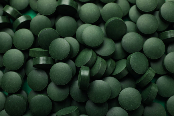 Spirulina in pills on whole background, close up - Foto, afbeelding
