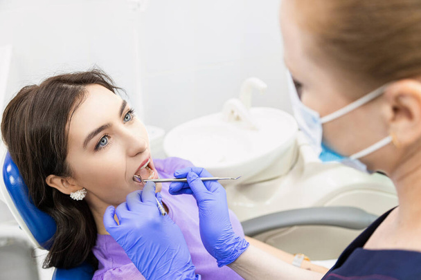 Dentistry concept. Professional dental services and modern equipment without pain. The doctor consults and treats the young woman, conducts an examination and draws up a treatment plan - Фото, зображення