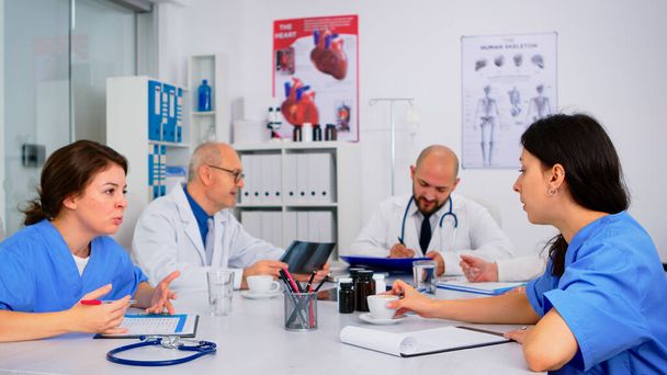 Pielęgniarki medyczne mające spotkanie z lekarzami w białych fartuchach laboratoryjnych - Zdjęcie, obraz