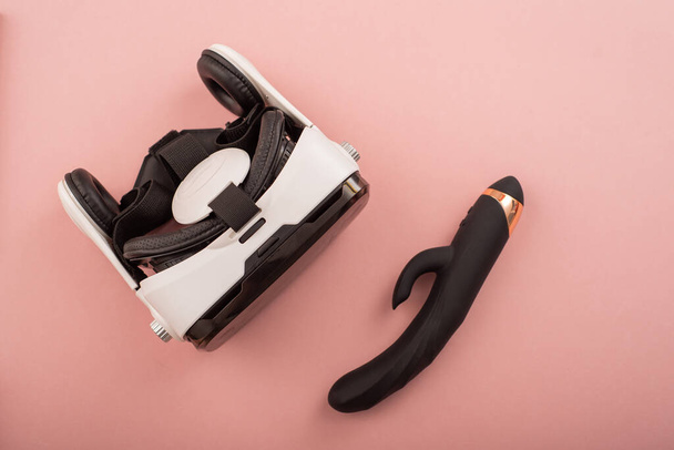 Black dildo and virtual reality helmet on a pink background. Masturbation concept with modern technology - Foto, afbeelding