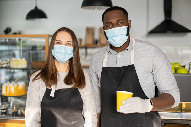 A waitress and a waiter in a medical masks - 写真・画像