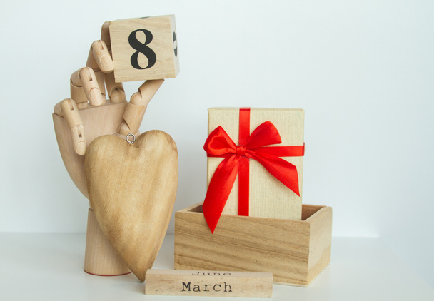 Holzhandmodell, großes Herz und Schreibtischkalender aus Holz mit Zahlen, Datum 8. März - weiblicher Mutterleib - Foto, Bild