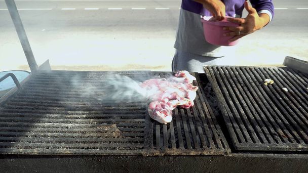 Čerstvé červené maso se griluje na dřevěném uhlí. Muž dává syrové maso na gril. Kouř ze smažení - Fotografie, Obrázek